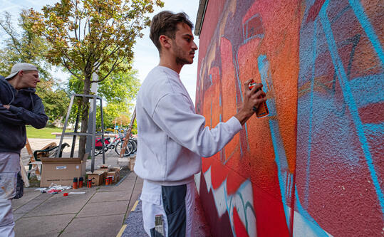 Berufsschüler sprayen Graffiti unter professioneller Anleitung